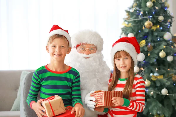 Weihnachtsmann und seine kleinen Helfer mit Geschenken im weihnachtlich dekorierten Raum — Stockfoto