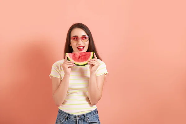 Mooie jonge vrouw met een stukje verse watermeloen op kleur achtergrond — Stockfoto