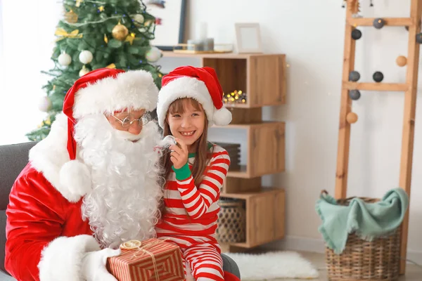 Święty Mikołaj i dziewczynka z darem w pokoju udekorowane na Boże Narodzenie — Zdjęcie stockowe