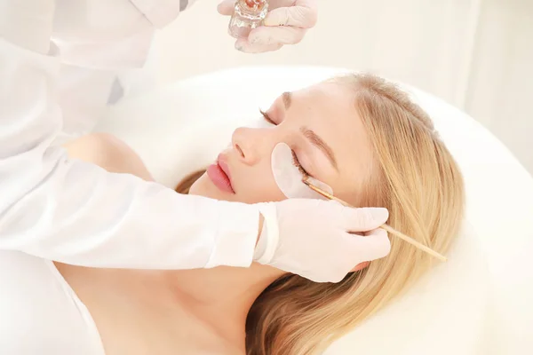 Young woman undergoing procedure of eyelashes dyeing in beauty salon — Stock Photo, Image