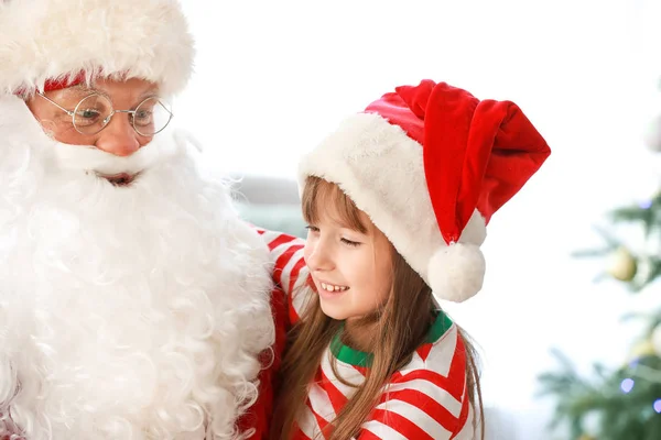 Jultomten och liten flicka i rummet dekorerad för julen — Stockfoto