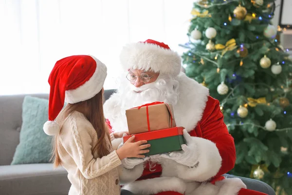 Santa Claus con regalos y niña en la habitación decorada para Navidad — Foto de Stock