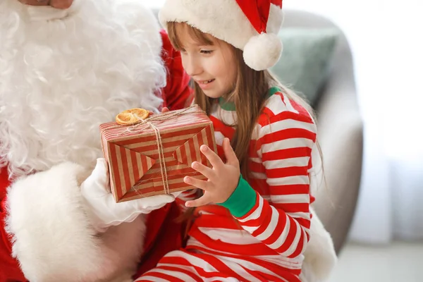 サンタクロースとクリスマスのために飾られた部屋で贈り物を持つ小さな女の子 — ストック写真