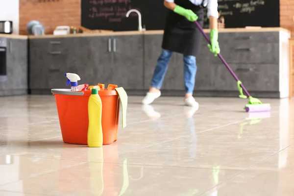 Set of cleaning supplies on floor in kitchen — Stock Photo, Image