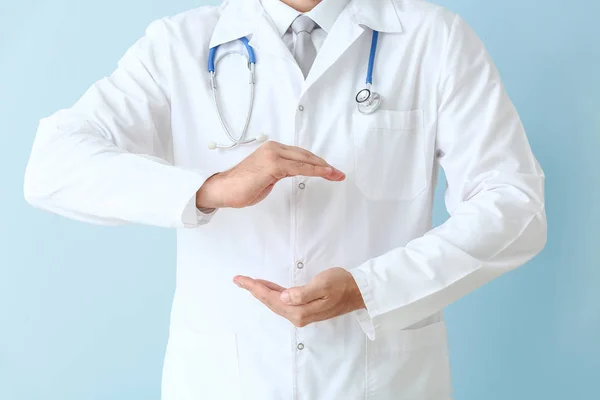 Mužský lékař, který drží něco proti barevnému pozadí, zaostřená — Stock fotografie
