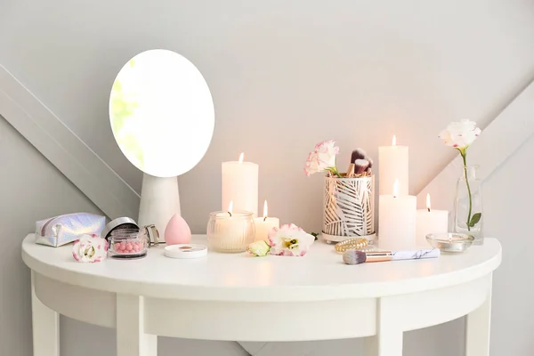 Beautiful burning candles and cosmetics on dressing table — Stock Photo, Image