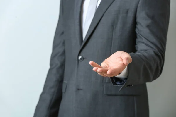 Geschäftsmann hält etwas vor hellem Hintergrund, Nahaufnahme — Stockfoto