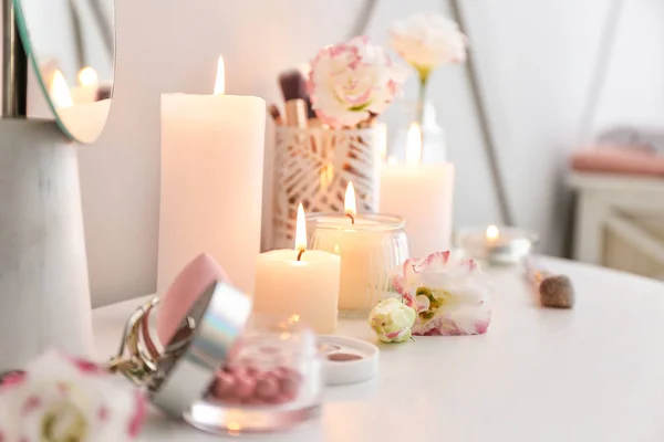 Beautiful burning candles and cosmetics on dressing table — Stock Photo, Image