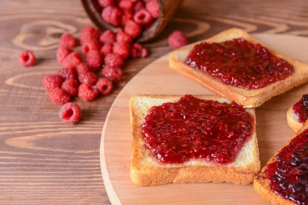 Savoureux pain grillé et confiture de framboises sur planche de bois — Photo