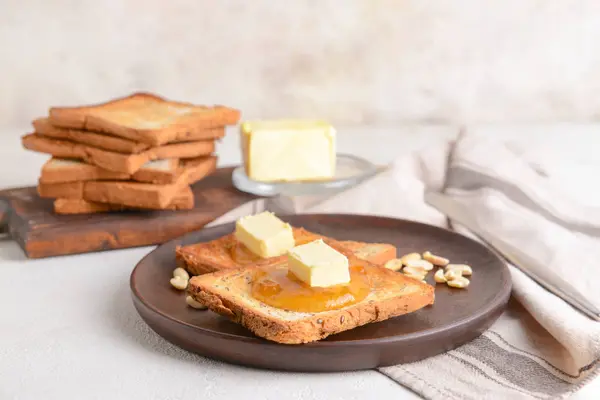 Plate with tasty toasted bread, butter and jam on table — Stock Photo, Image