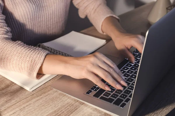 Woman working on laptop at table in evening, closeup — Stock Photo, Image