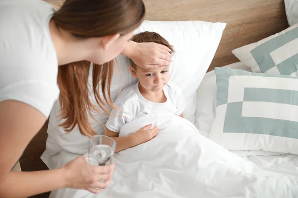 自宅でインフルエンザにかかっている小さな息子の世話をしている母親 — ストック写真