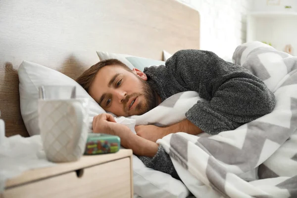 Человек, больной гриппом, лежит в постели — стоковое фото