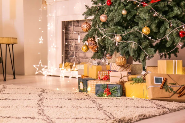 Many gift boxes under Christmas tree in room — Stock Photo, Image