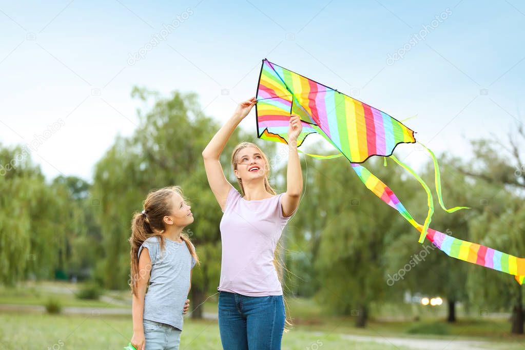 Young woman with little daughter flying kite outdoors