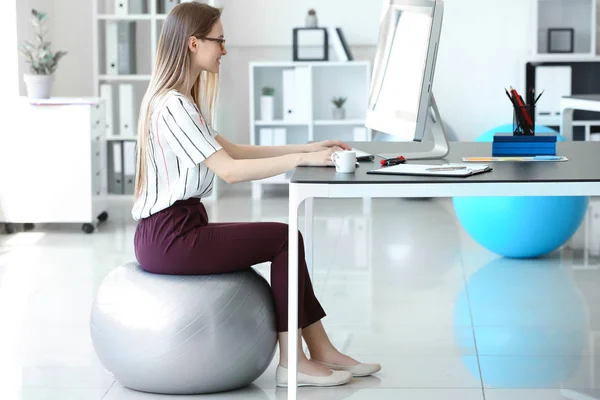 Ung affärskvinna sitter på Fitball medan du arbetar i Office — Stockfoto