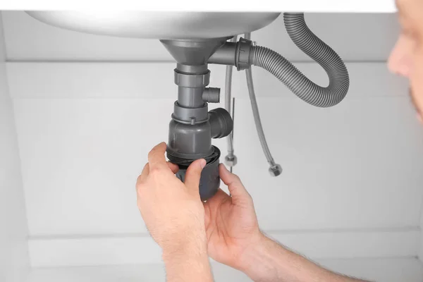 Plumber repairing pipes in kitchen — Stock Photo, Image