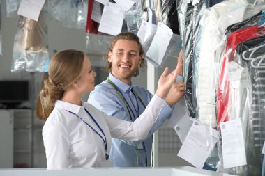 Modern kuru temizlemeci işçileri giysilerle rafa yakın
