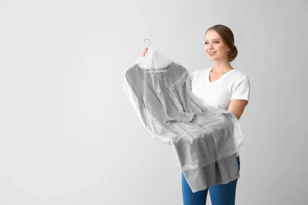 Vrouw met kleren na chemisch reinigen op lichte achtergrond — Stockfoto