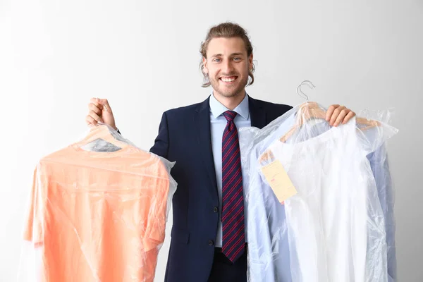 Man with clothes after dry-cleaning on white background