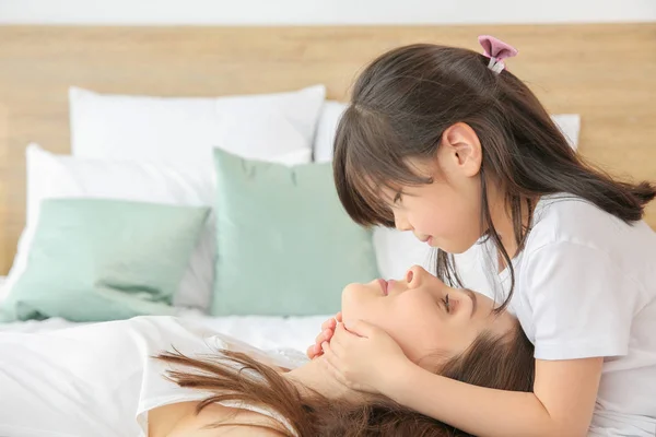 Klein meisje met haar moeder op bed thuis — Stockfoto