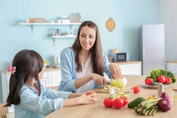 Mother with cute daughter preparing vegetable salad in kitchen — Stock Photo, Image