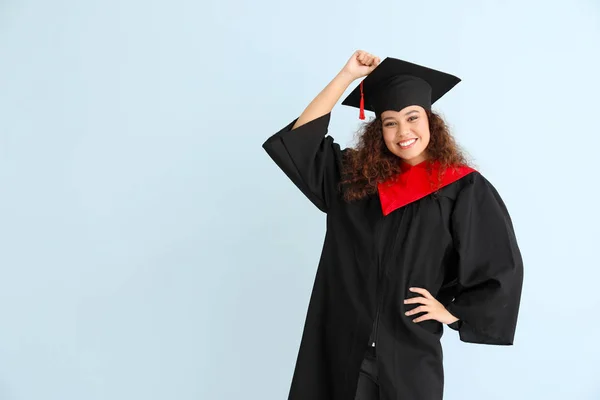 Ung afroamerikansk student i ungkarlskappa på färg bakgrund — Stockfoto