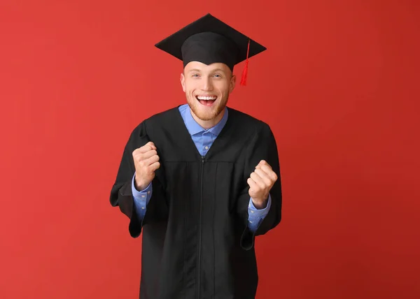Szczęśliwy męski student w Kawalerskim szacie na kolorowym tle — Zdjęcie stockowe