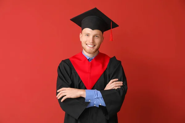 Joven estudiante masculino en bata de soltero sobre fondo de color — Foto de Stock