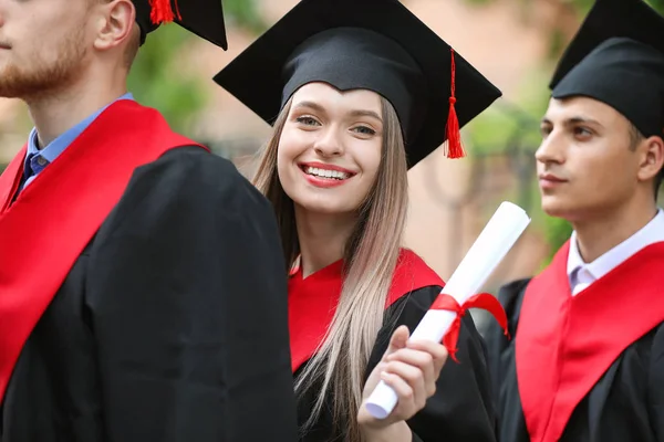 Boldog diákok Bachelor köpenyekben szabadban — Stock Fotó