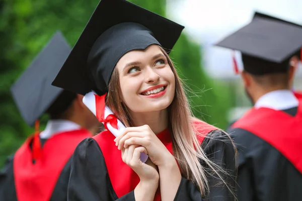 Studentka w szacie kawalerski i dyplom na zewnątrz — Zdjęcie stockowe