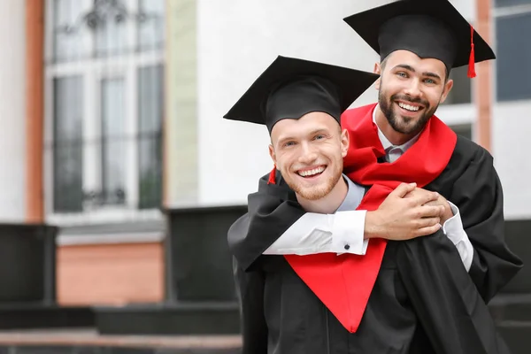 Young students in bachelor robes outdoors — Stock Photo, Image
