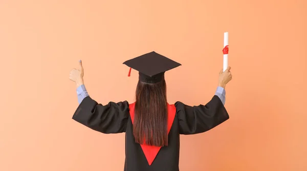 Выпускница с дипломом по цветному фону — стоковое фото