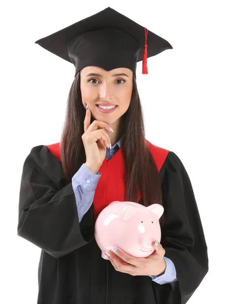 Vrouwelijke afgestudeerde met Piggy Bank op witte achtergrond. Collegegeld kosten concept Stockfoto