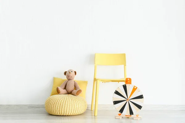 Cadeira com pufe e brinquedos perto da parede de luz no quarto das crianças — Fotografia de Stock