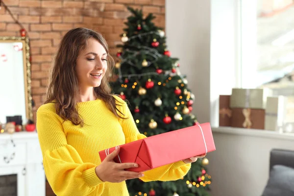 Gelukkige jonge vrouw met kerstcadeau thuis — Stockfoto