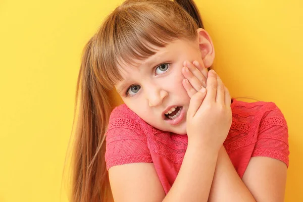 Kis lány szenved fogfájás a színes háttér — Stock Fotó