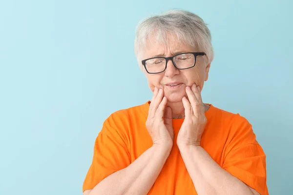 Mulher idosa que sofre de dor de dente contra fundo de cor — Fotografia de Stock