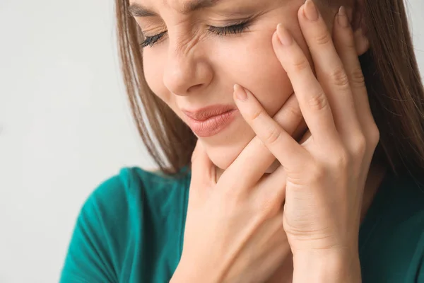 Young woman suffering from toothache against light background, closeup — Stock Photo, Image