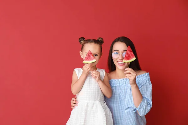 Beautiful young woman and cute little girl with fresh watermelon on color background — Stock Photo, Image