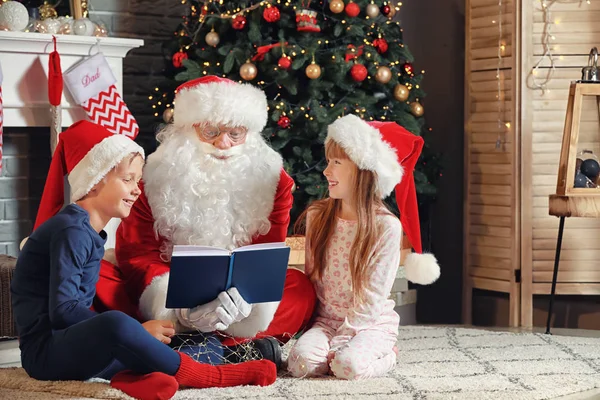 Santa Claus and little children reading book in room decorated for Christmas — Stock Photo, Image