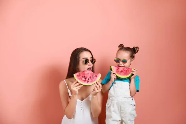 Bella giovane donna e carina bambina con anguria fresca su sfondo di colore — Foto Stock