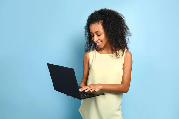 Portrait of beautiful African-American woman with laptop on color background — Stock Photo, Image