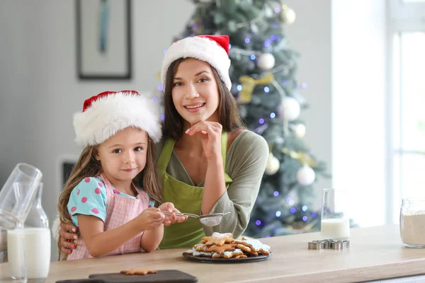 Kvinna och hennes lilla dotter förbereder julkakor hemma — Stockfoto
