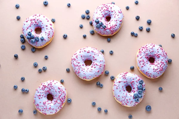 Süße leckere Donuts und Beeren auf farbigem Hintergrund — Stockfoto