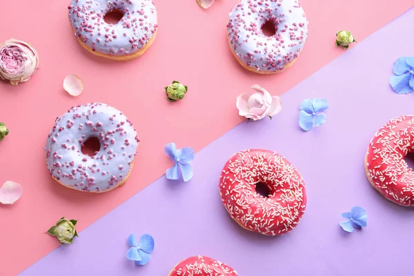Doce saboroso donuts e flores no fundo de cor — Fotografia de Stock