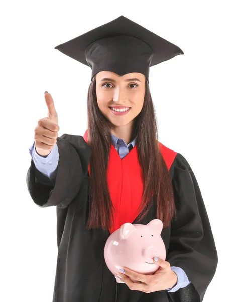 Vrouwelijke afgestudeerde met Piggy Bank met duim-up op witte achtergrond. Collegegeld kosten concept Rechtenvrije Stockfoto's