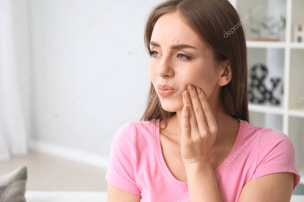 Young woman suffering from toothache at home