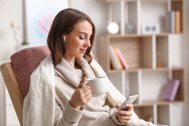 Evde müzik dinlerken çay içen güzel genç kadın