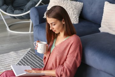 Güzel genç bayan evde çay içiyor.